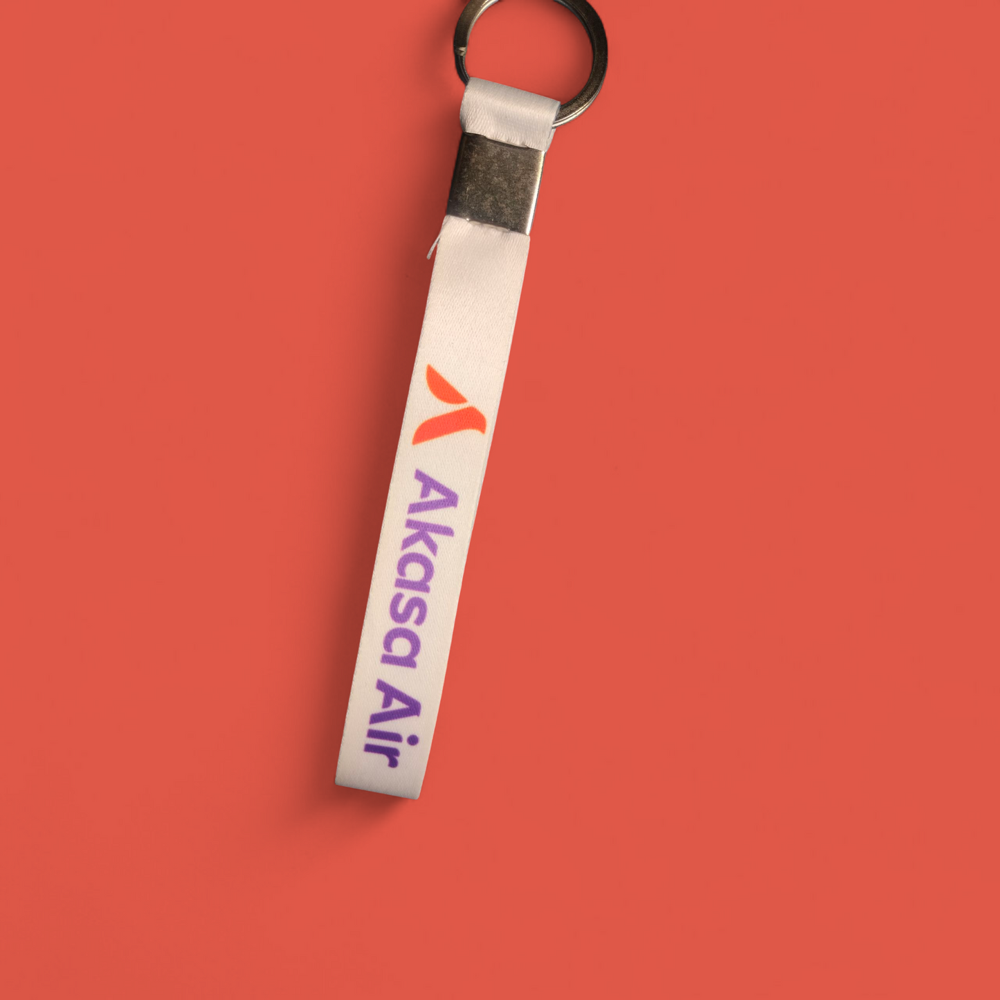 White Akasa Air satin keychain with purple and orange branding on red background