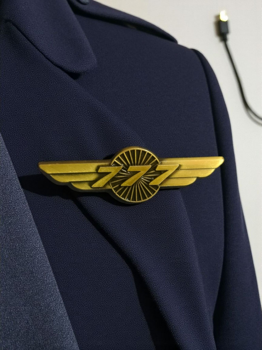 Gold Boeing 777 wing pin on a fabric background, symbolizing aviation and pilot recognition